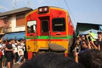 NKF 1227 (1A' 2', dh, Fuji Heavy Industries, Bauj.1985) als erstes Fahrzeug des ORD 4385 von Ban Laem erkämpft sich am 20.November 2019 bei der Mae Klong Station seinen Weg durch die, mit Bussen angescharten, Touristen.