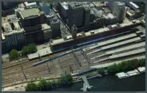 Der Bahnhof Flinders Street ist der bedeutendste Bahnhof Melbournes und befindet sich im Stadtzentrum am Yarra River. Das im Stile der Neorenaissance errichtete Bahnhofsgebäude mit dem markanten Uhrenturm wurde 1910 eingeweiht. Zwei X'Trapolis 100-Triebzüge der Metro Trains Melbourne verlassen am 29.12.2019 den Bahnhof. (aufgenommen aus dem 297 m hohen Eureka-Tower)