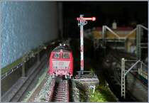 In meinen alten Beständen fanden sich noch einige Märklin mini club Flügelsignale (8940), davon waren zwei noch funktionsfähig, so dass ich sie in meine Anlage integrierte, was gar nicht so einfach war, nicht etwa da es kompliziert gewesen wäre, die farbigen Drähte entsprechend anzuschliessen, doch bei der Gestaltung und Planung der Anlage vor zehn Jahren hatte ich beschlossen, keine Schaltgeleise im sichtbaren Bereich einzubauen. Folglich musste für die im automatischen Pendelbetrieb bediente Strecke ein Schaltgeleis VOR dem Signal dieses nicht nur auf Fahrt stellen, sondern mit dem gleichen Schaltbefehl (verzögert) wieder schliessen. So musste ich die verschieden Stromsorten (5 V DC, 10 V AC, 16 V DC/AC entsprechend meinen Bedürfnissen gerecht zu nutzen. Vor einigen Jahren bereits versucht, mit einem Zeitimpulsverzögerer das Problem zu lösen, explodierte damals ein Kondensator, so dass ich dieses Mal etwas vorsichtiger und behutsam (Tests/Fachliteratur) zu Werke ging. Nun - die Schaltung klappt und nun gilt es den Antriebskasten des Signal noch etwas zu tarnen… 

14.Feb. 2020
