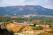 Kurz nach dem Talgo Madrid - Gijon startet um 15.35 der Talgo nach Santander seine Reise, er wird um 21.56 ankommen.
Im Hintergrund liegt San Lorenzo de El Escorial. Wieder ist das Führende Triebfahrzeug ein  Japonesa , ein 269 der ersten Bauserie. Oktober 1983