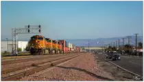 BNSF 5168 GE C44-9W (Dash9-44CW) + BNSF 4333 GE C44-9W + BNSF 4811 GE C44-9W + BNSF 4541 GE C44-9W ziehen einen langen Containerzug, von San Bernardino in Richtung Cajon Pass. 
Rechts im Bild ein kurzer Abschnitt der legendären Route 66, welche von Chicago (Illinois) nach Santa Monica/LA (Kalifornien) führt. Sie ist 2451 Meilen (3945 Kilometer) lang und wird als  The Mother Road  bezeichnet.  
San Bernardino 19.10.2019