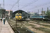 Mittags, etwa ab 13.30 Uhr, herrschte Hochbetrieb am Bahnhof Madrid Atocha. Es fuhren Züge ab in die großen andalusischen Städte und in die Extremadura. Lok 269 226, eine Vertreterin der letzten Bauserie 269 222 bis 269 331, beginnt gerade ihre Reise ins 727 km entfernte Cadiz. Am Zughaken hat sie den Talgo Pendular 110. Ganz rechts sehen wir einen TER, einen Dieseltriebwagen italienischer Herkunft, links im Hintergrund steht eine von Krauss Maffei gebaute Diesellok mit dem Talgo III nach Granada und Almeria. Oktober 1983. 
Canon AE1, Canoscan, GIMP.