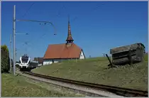 Der TPF RABe 527 198  BCF / FKB  (Kantonalbankwerbezug) erreicht Vaulruz, links im Bild die mittlerweile bekannte Kapelle von Vaulruz, rechts, die hier typischen an den Gleisböschung stehenden Bretterstapel. 

19. Mai 2020