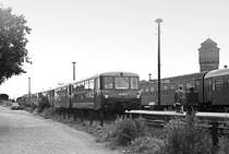 26. Juli 1984, im Bahnhof Neustadt/Dosse steht ein aus vier  Ferkeltaxen bestehender Zug. Er kam 12:19 Uhr als 15356 von Neuruppin und wird 12:57 Uhr als 15357 dahin zurückfahren. Die Reisenden am Bahnsteig warten auf D935, der von Schwerin kommt und 12:37 Uhr über Potsdam nach Dresden fahren wird. Gut, dass ich das Kursbuch noch habe. 