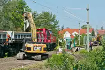 F�r das neue Gleisbett, das tiefer sein wird als das Alte, schiebt eine Planierraupe eine Erdschicht zu einem Bagger, der diese aufnimmt und in Sch�ttgutkippwagen der Gattung Uas leert.