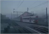 Bei dichtem Nebel und noch in der Morgendämmerung erreicht der TPF Be 4/4 121 mit dem B 207 (ex MOB), B209 (ex MOB) und dem ABt 221 den Bahnhof von Broc Village. Der Zug ist als RER 60 14954 von Bulle nach Broc Farbrique unterwegs. 

26. Nov. 2020