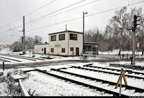 Ansichten der Blockstelle (Bk) Zscherben kurz vorm Baustart
Das Gleisbildstellwerk der Bauart GS II DR von WSSB steht direkt am örtlich bedienten Bahnübergang (Bü) Teutschenthaler Straße. In dem Gebäudeteil mit den alten Türen befand sich früher eine Wartehalle. Im linken Anbau haben womöglich die Relais zur Steuerung der Anlagen ihren Platz.
Das am rechten Rand erkennbare Blocksignal  A  Richtung Teutschenthal ist mittlerweile übrigens Geschichte. Es wurde durch ein neues Hl-Signal ersetzt, das vor die Bahnsteiganlagen und damit etwas weiter weg vom Bü gesetzt wurde.

🚩 Bahnstrecke Halle–Hann. Münden (KBS 590)
🕓 3.1.2021 | 11:42 Uhr