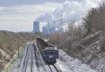 RWE Power 506 schiebt am 12.02.2021 bei Sinsteden einen Braunkohlezug in Richtung Süden. Im Hintergrund das Kraftwerk Niederaußem, lt. wikipedia das zweitleistungsfähige Kraftwerk Deutschlands, das 2015 mit einem CO2-Ausstoß von 27,3 Mio. Tonnen die dritthöchsten Treibhausgasemissionen aller europäischen Kraftwerke versachte.