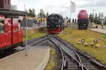 Rangiermanöver am 22.08.2020 im Brockenbahnhof (Bild 1): Da unseer Sonderzug, wie für einen solchen üblich, zusätzlich zum Normalfahrplan verkehrt, wird es auf den drei Gleisen des Brockenbahnhofes eng. Da links, auf Gleis 1, P 8922 nach Drei Annen Hohne steht und rechts, auf Gleis 3, bereits P 8920 (nicht im Bild) eingefahren ist, muß unser Sonderzug jetzt aus Gleis 2 auf die offene Strecke vorziehen, um das Umsetzen von 99 236, zur Übernahme des Wernigeröder Zuges, welcher den Brocken vor uns verlassen soll, zu ermöglichen. Danach wird unser Zug wieder auf Gleis 2 zurückgeschoben, sodaß P 8930 den Bahnhof fahrplanmäßig verlassen kann. Daraufhin folgt dann unser Zug im Blockabstand. Im Hintergrund ist der Feuerloschwagen (Regelspurwagen auf Rollwagen) zu sehen, der gemeinsam mit seinem  Zwillingsbruder  im Bahnhof Drei Annen Hohne, zügige Aufnahme der Löscharbeiten bei Bränden im unzugänglichen Waldgebiet ermöglicht. (Aufnahme von der hintersten Plattform des Sonderzuges)