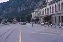 Ein imposantes Gebäude ist der Bahnhof von Brig. Der Eingang erfolgt ebenerdig, die Gleise der SBB und BLS liegen in Hochlage, gleichsam im ersten Stock. Nicht minder interessant ist der Bahnhofsvorplatz: Hier ist der Gemeinschaftsbahnhof von BVZ und FO - heute zur MGB - Matterhorn-Gotthard-Bahn - fusioniert. Damals mußte der Glacierexpress Chur - Zermatt in Brig  Kopf machen . Die Lokomotive mußte den Zug umfahren, nicht ganz einfach auf dem Bahnhofsvorplatz! Im Zuge von Bahn 2000 wurde der Platz umgestaltet, aus dem Kopfbahnhof der FO-BVZ wurde ein Durchgangsbahnhof. Auch das im Hintergrund erkennbare Depot der Schmalspurbahnen existiert an dieser Stelle nicht mehr.
Brig, 28. Juni 1988; Canon AE-1, Canoscan, Gimp