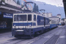 Auf der dem Genfer See abgewandten Seite des Bahnhofs von Montreux befindet sich der Ausgangspunkt gleich zweier Schmalspurbahnen. Mitten im Bild liegen drei Gleise der Montreux-Oberland-Bernois Bahn, abgekürzt MOB - und ganz links, unter der Terasse des Hotel Terminus, ist Endpunkt der Zahnradbahn Glion-Caux-Rochers de Naye. Die Lokomotive GDe 4/4 der Reihe 6000 war zur Zeit der Aufnahme gerade 4 Jahre alt und auf dem neuesten Stand der Technik. Lange Zeit hielt diese Baureihe sogar den Geschwindigkeitsrekord für Schweizer Schmalspurbahnen. Im Zuge von Bahn 2000 wurden die Bahnanlagen von Montreux gründlich umgestaltet.
Montreux, 24.08.1987; Canon AE-1, Canoscan, Gimp