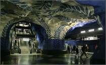 Blaue Linie, Stammstrecke, Station  T-Centralen  - 

Blick in die Bahnsteigebene dieses Bahnhofes mit der auffälligen Bemalung der Spritzbetonflächen. Die Treppeanlag führt zu dem Verbindungstunnel, der mit die Blaue Linien mit den anderen T-Bahnlinen verbindet. An der Ostseite gibt es einen Ausgang zum Sergels Torg, an der Westseite zum Bahnhof Stockholm C. Die Bahnsteige der Blauen Linie liegen hier 29 Meter unter der Oberfläche bzw. 24 Meter unter Meeresoberfläche. Darunter soll noch eine viergleisge Station für den Pendeltåg entstehen. Als erste Strecke der Blauen Linie ging am 31.9.1975 der Abschnitt T-Centralen - Hallonbergen - Hjulsta in Betrieb. 

24.8.2007 (M)