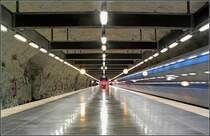 Blaue Linie, Strecke nach Akalla, Station  Hallonbergen  - 

Blick in die Mittelbahnsteighalle (Stadteinwärts-Richtung) der dreigleisigen Station. Hier zweigt eine 2,6 km lange Betriebsstrecke zur Station Rinkeby am zweiten Streckenast der Blauen Linie ab. Mit dieser Betriebsstrecke wird das Rissnedepan angeschlossen. Das Depot liegt zum Teil unterirdisch in vier parallelen zweigleisigen Felstunnels. Ursprünglich gab es auch Fahrgastverkehr über diese Strecke. Als erster Abschnitt der Blauen Linie ging 1975 die Strecke T-Centralen - Hallonbergen - Betriebsstrecke - Rinkeby - Hjulsta in Betrieb. Erst 1985 wurde der Hjulsta-Streckenast über die Zwischenstrecke Västra skogen - Rinkeby angeschlossen. 

24.8.2007 (J)