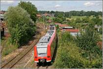 P�nktlich verl�sst 425 148/648 als RB 30226 von Rosenheim nach Holzkirchen den Bahnhof Richtung Bad Aibling. Der Schrotth�ndler links im Bild bekommt sogar noch Waggons zugestellt.