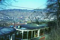 END Straßenbahn Esslingen-Nellingen-Denkendorf__Die aber auch nach Scharnhausen und Neuhausen fuhr.__Neubau-Zug unterhalb der Ausweichhaltestelle 'Zollberg'. Im Tal das Bahnhofsgelände, darüber die Weinberge.__04-03-1976 