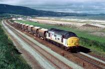 Am 26. August 1996 fahrt 37413 entlang der walisische Kueste mit einem Schotterzug aus Penmaenmawr.