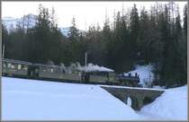 Noch vor Sonnenaufgang rattert der vollbesetzte Dampfextrazug 2122 Berg�n entgegen und passiert soeben die Schlittlebahn�berf�hrung von Darlux. (20.02.2008)