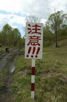 Am h�chstemn Punkt halten die Z�ge, um die Schiebelok abzukuppeln und die Handbremsen der ersten vier Wagen anzuziehen. Das Schild sagt  Halt!  Der Mann auf dem Gleis ist ein Kr�utersammler der seine  Beute  z�hlt. Oft fahren die dann auf den Kohlewagen ins Tal.