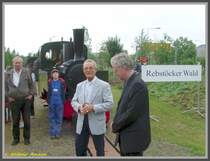 Am 31.05.2008 beging das Feldbahnmuseum Frankfurt am Main die offizielle Er�ffnung des mit dem ersten Spatenstich am 05.06.2004 begonnen neuen Streckenabschnitts bis zum Messeparkhaus mit einem Feldbahnfest. Als Stellvertreter der Stadt Frankfurt am Main hielt der Stadtrat B�rger (im hellgrauen Sakko vor der Lokomotive) eine Ansprache, nachdem der Vorsitzende des Feldbahnmuseums (rechts neben ihm stehend) vorher desgleichen getan hatte. Der neue �stliche Endpunkt der Strecke befindet sich neben dem Messe-Wohnmobilstellplatz und tr�gt den Namen  Rebst�cker Wald . Der Rebst�cker Wald lag �stlich der Feldbahnstrecke und grenzte fr�her direkt an den heutigen Endpunkt. Ein kleines Restst�ck am ehemaligen Batelle-Institut ist heute noch vorhanden.