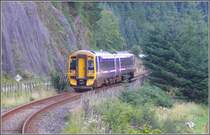 158 721 ist soeben an mir vorbei gerumpelt und passiert mit Stahlnetzen bewehrte Felspartien entlang des Loch Carron. Der Schaffner scheint die Aussicht aus dem hinteren F�hrerstand zu geniessen. (06.08.2008)