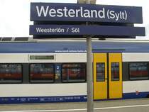 Das Bahnhofsschild von Westerland auf Sylt mit einem NOB Regionalzug im Hintergrund am 05.08.2008.