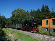 Hier passiert 99 1715 die Fahrzeughalle in Schl�ssel, im Hintergrund das Ersatzteillager der IG Pressnitztalbahn, 31.08.2008