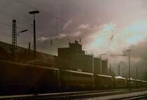 Ausschnitt einer Abstellgruppe im Bw Hagen Eck etwa um 1980, kurz vor einer aufziehenden Kaltfront....
Damals, konnte man noch Fahrzeuge, der verschiedensten Baureihen,
in allen m�glichen Farben, antreffen.
Im Hintergrund befinden sich die Treibstofftanks, f�r  durstige 
Dieselloks. Das dunkle Geb�ude, ist das ehemalige Depot der Hagener Strassenbahn.
Es ist auch heute, alles noch vorhanden, bis auf die Lok�s. Dort stehen heute, meist G�terwagen, die auf Ausbesserung warten; oder
das Unkraut erfreut sich ungest�rtem Wachstums.....

