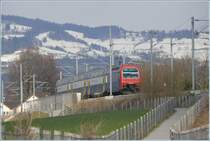 Re 450 060-9 als S5 nach Rafz �berquert soeben die Br�cke �ber den Schiffskanal der Unter- und Obersee verbindet. Wegen des Vogelschutzgebietes entlang des Z�richseeufers kann der Seedamm hier nur in geordneten Bahnen �berquert werden, darum die vielen Z�une. (26.03.2009)