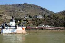 Bis 1866 diente der Pfalzgrafenstein bei Kaub als Zollstation. Er wurde 1327 von Ludwig, dem Bayern mitten im Rhein auf einer Insel errichtet. Der Winter 1813/14 r�ckte die Burg ins Zentrum europ�ischer Geschichte. Dem preu�ischen Generalfeldmarschall Bl�cher gelang hier mit seinem Heer der Rhein�bergang, welcher den Sturz Napoleons einleitete. Gleich passiert eine Regionalbahn die historische St�tte. (Blick von der Autof�hr-Anlegestelle Kaub auf der linken Rheinseite, April 2009).