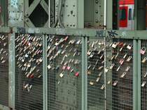 Liebesschl�sser. Sie h�ngen inzwischen zu hunderten an der Hohenzollernbr�cke. Hier h�ngen Paare ein Schloss in das Gitter welches den Fu�weg �ber die Br�cke von den Gleisen trennt, schw�ren sich ewige Treue und werfen dann den Schl�ssel in den Rhein.