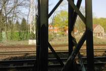 Ein oranges Haus in der N�he der Bahn betrachtet durch das Stahlger�st eines Mastes.