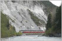 RE1240 mit Ge 4/4 II 626  Malans  passiert die riesige Schutthalde bei Trin, wo das Geleise durch eine hohe Schutzmauer vom unstabilen Hang getrennt wird. (17.04.2009)