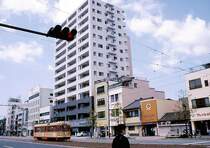 Matsuyama Strassenbahn (Insel Shikoku): In wenigen Jahren wuchsen die H�user dieser kleinen Burgstadt wie Orgelpfeifen von ganz klein (rechts) zu riesig (links). Die einst wuchtig wirkende Strassenbahn wird proportional immer winziger. Wagen 2003 am 8.April 2008. 