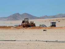 Auf der S�dbahn nach L�deritz geht es hoch her! An manchen Orten wird am neuen Bahndamm f�r die neu zu verlegenden Schienen gebaut. Dies geschieht im offenen (W�sten-)Gel�nde  nach Strassenbaunormen. Nichts geht ohne Wasser! Im Vordergrund eine Pipeline, die das kostbare Nass zu denn einzelnen Bauabschnitten leitet.