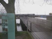 2001 wurde der Holzsteg parallel zum Rapperswiler Seedamm er�ffnet. Beim Start dieses Holzstegs ist eine Infotafel montiert, die �ber die Geschichte der Rapperswiler Seequerung informiert. 1878 fuhr die erste Eisenbahn �ber den Seedamm. Allerdings verlor der Seedamm von seinem Glanz, und wird heute t�glich in den Verkehrsmeldungen am Radio er�whnt, wie sehr sich der Verkehr vor Rapperswil staut. Daneben f�hrt schier unscheinbar eine S5 Dotra nach Rafz �ber den Z�richsee am 26.11.09.