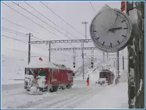 Es ist zehn vor drei und bitterkalt in Ospizio Bernina 2253m. W�hrenddem ABe 4/4 II 44 mit ihrem Spurpflug noch Gleis 1 freimacht, wird Gem 4/4 801  Steinbock  vom Schleuderschnee befreit. (01.12.2009)