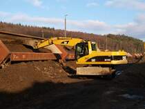 Mit einem Bagger mu� bei entladung des Bauzuges geholfen werden, weil die Ladung festgefroren ist und nur zum Teil aus den Mulden rutscht.