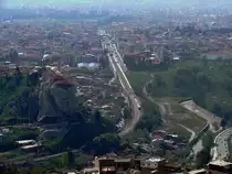 Blick von der historischen Festung Kadifekale in Izmir nach S�dosten.
Am dem Felshang gegen�ber entsteht gerade ein �berdimensionaler Atat�rk-Kopf, was 
doch gew�hnungsbed�rftig wirkt.
Davor ist auf der nach Osten f�hrende Bahnstrecke Richtung Flughafen-Izmir und Selcuk/Aydin eine Dreifachtraktion der Dieseltriebwagen Reihe MT-5700 unterwegs.
Gut zu erkennen ist, dass die Bahnstrecke hier ausgebaut und tiefergelegt wurde. Die Elektrifizierung f�r den Vorortverkehr ist allerdings bisher etwas steckengeblieben und nur teilweise fertig.
16.04.2009  Izmir-Kadifekale
