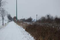 Kurz hinter dem Bahnhof Kapellen in Richtung Neuss kommt einer der zahlreichen Feldwegbahn�berg�nge an der Erftbahn. Besonders sch�n sind die immer noch vorhandenen Telegraphenmasten. Foto vom 13.2.2010