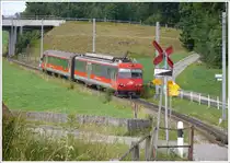 Nach dem �berqueren der Kantonsstrasse bei der Haltestelle Kreuzstrasse beginnt ein neuer Zahnstangenabschnitt bis hinauf zum Stoss.R3094 mit BDeh4/4 16 und ABt 116 klettert bergw�rts. Der Bahn�bergang �ber die viel befahrene Strasse wird ohne Schranke und Lichtsignal gequert, Schritttempo, ein Achtungspfiff und die rote Farbe des Zuges gen�gen offenbar. (28.07.2010)