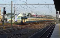 Serie 111 u. 113: Zwischen 1963 und 1982 gebaute Z�ge f�r den Lokalverkehr auf Flachlandstrecken. Insgesamt rund 2900 Wagen; zahlreiche Umbauten und Modernisierungen bis 2001. Nach 64 Z�gen Serie 111 erhielten die Motorwagenpaare st�rkere Motoren und die Serienbezeichnung 113; dazu passende nicht motorisierte Wagen wurden als Serie 111 weitergebaut. Ausmusterung ab den 1980er Jahren; im April 2008 waren 565 Wagen vorhanden. Heute zu 2-,3-,4- und 6-Wagenz�gen formiert (ein typischer Zug besteht aus Steuerwagen KUHA 111 + Motorwagenpaar MOHA 112 + MOHA 113 + Steuerwagen KUHA 111 [クハ111+モハ112+モハ113+クハ111)]. Im Bild: Ein 4+6-Wagenzug in Kisarazu, gef�hrt von Steuerwagen KUHA 111-1134, 27.November 2009. 