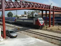 Eine JT42BW von GEC-Alsthom unterquert am 12.08.10 um die Mittagszeit mit ihrem Regionalzug aus der neuen Viaggio Light-Reihe die Fu�g�ngerbr�cke zum Eisenbahnmuseum der Israelischen Eisenbahnen im Bahnhof Haifa Mizrah.