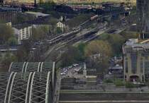 Blick auf den Bahnhof Köln-Deutz. Dieser Bahnhof ist doppelstöckig, links im Bild erkennt man ein Teil der unteren Bahnsteige, die sich unter den oberen fortsetzen. Rechts neben der Brücke ist der Ansatz der ehemaligen Straßenbrücke zu sehen. Es liegen da auch noch Straßenbahnschienen. 

Scan vom Dia, Teleaufnahme vom 9.4.2005, gefiltert mit Hochpass, Helligkeit, Kontrast- und Farbsättigung-Anpassung (Matthias)