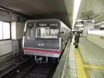 Midōsuji Line Series 21 Zug in der Haltestelle Shin-Osaka, von wo aus er in Richtung Tennoji abfahren wird. Der Zugbegleiter kontrolliert mit der  Zeige-und-Best�tige -Methode den korrekten Halt des Zuges und wird gleich die Abfahrt kontrollieren und einleiten.