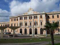 Bahnhof Sassari von der Stra�enseite am 20.10.2005, davor eine neue Meterspur-Haltestelle mit  Betonpilzen , neu elektrifiziert, aber alte Gleise, die mit denen im Bahnhof verbunden sind. Hier wird anscheinend eine Strecke reaktiviert, die erste Elektrische auf Sardinien.