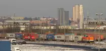 Links steht MaK G 1000 BB DH 712 HGK und rechts zieht 201 878-6 (Locon 209) einen Containerzug Richtung Rbf Alte-S�derelbe. Im Hintergrund ist die Stadtkulisse Hamburgs zu erkennen und rechts neben den Hochh�usern die Kirchturmspitze des Hamburger Michels. Aufgenommen am 4.12.10 von einer Fu�g�ngerbr�cke beim CT Waltershof.