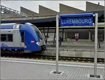 Harmonie in blau am 26.09.2010 im Bahnhof von Luxemburg. Die SNCF Computermaus passt farbllich sehr gut zum neuen Bahnhofsschild. Leider war das Schild nur ein Provisorium, am 02.12.2010 standen nur noch die leeren Pfosten am Bahnsteig. (Hans) 