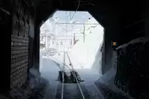 14.01.2010 - Einfahrt in den Bahnhof Ospizio Bernina. Links neben dem Tunnel ist die Schneefr�sse in einem Schopf  versteckt . Bild wurde aus dem Fahrgastraum aufgenommen. Im Allegra hat der Fahrgast eine Scheibe, durch welche man wunderbar auf die Strecke sehen kann.