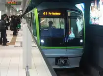 Fukuoka U-Bahn Serie 3000, Nanakuma-Linie. Diese 2005 eröffnete Linie ist einstweilen 12,0 km lang und führt von Fukuoka aus nach Süden; 1435mm-Spur, Oberleitung. Die Züge verkehren vollautomatisch; der im Bild vorne im Zug sichtbare Beamte fährt nur zur Ueberwachung und als Ansprechperson mit. Es gibt 17 4-Wagenzüge, die vom deutschen Designer Alexander Neumeister entworfen wurden. Bild: Zug mit Frontwagen 3115 in Minami Tenjin (Stadt Fukuoka), 17.März 2007. 