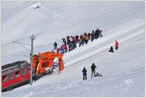 Der ausgefahrene R�umer leitet den Schnee in die Mitte des Geleises, von wo er anschliessend durch die Schneeschleuder weggeschleudert wird und die Fotografengruppe ahnt noch nichts vom kommenden Unheil. (26.02.2011)